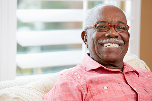 African american man wearing red shirt and glasses smiling big at the camera